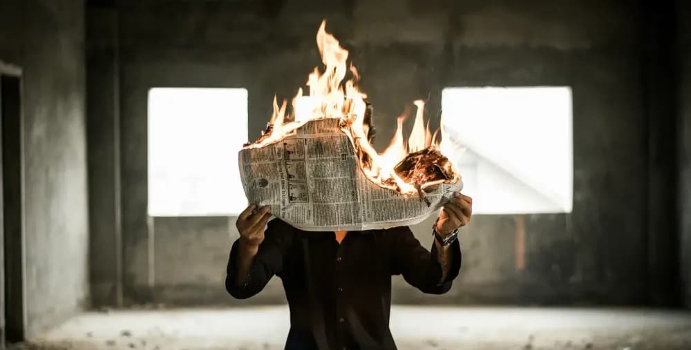 Photographie d'un homme tenant un journal qui brûle par Nijwam Swargiary